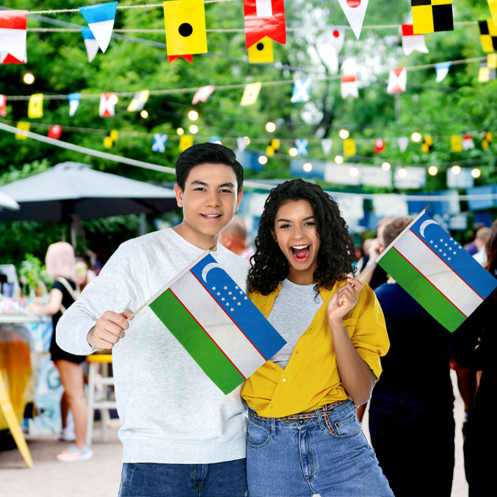 Man & Woman holding Uzbekistan Stick Flags 12in by 18in on 24in Wooden Dowels at Outdoor Fair